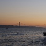 The 25 de Abril Bridge with the Christo Reo statue at sunset.